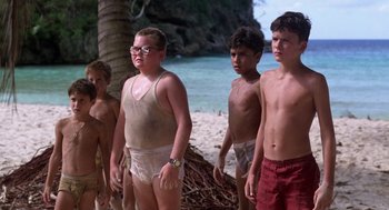 Movie still from “Lord of the Flies” (1990), directed by Harry Hook – A group of young people standing on a beach; Medium shot, Low angle