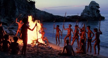 Movie still from “Lord of the Flies” (1990), directed by Harry Hook – A group of naked people standing around a fire; Wide shot, High angle