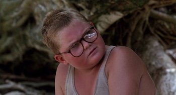 Movie still from “Lord of the Flies” (1990), directed by Harry Hook – A young boy with glasses is sitting down; Close Up shot, Low angle