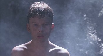 Movie still from “Lord of the Flies” (1990), directed by Harry Hook – A young boy is standing in the mist of a pool; Close Up shot, Low angle