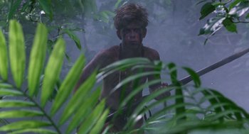 Movie still from “Lord of the Flies” (1990), directed by Harry Hook – A man in the woods with a machete in his hand; Wide shot, Low angle