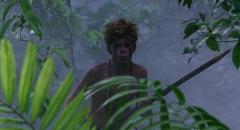 Movie still from “Lord of the Flies” (1990), directed by Harry Hook – A man in the woods with a spear; Medium shot, Low angle