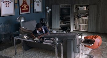 Movie still from “Love & Basketball” (2000), directed by Gina Prince-Bythewood – A man sitting at a table in a living room; Wide shot, High angle