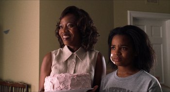 Movie still from “Love & Basketball” (2000), directed by Gina Prince-Bythewood – A woman and a child holding a pink cake; Medium shot, Over the shoulder angle