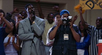 Movie still from “Love & Basketball” (2000), directed by Gina Prince-Bythewood – Two men are taking a picture with a digital camera; Medium shot, Low angle