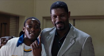 Movie still from “Love & Basketball” (2000), directed by Gina Prince-Bythewood – A man standing next to another man holding a cell phone; Close Up shot, Low angle