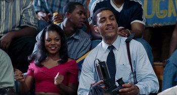 Movie still from “Love & Basketball” (2000), directed by Gina Prince-Bythewood – A group of people sitting in front of each other; Medium shot, Low angle