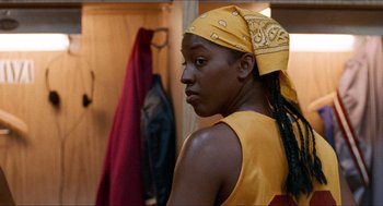 Movie still from “Love & Basketball” (2000), directed by Gina Prince-Bythewood – A woman in a yellow shirt and a bandanna is standing in front of a closet; Close Up shot, Over the shoulder angle