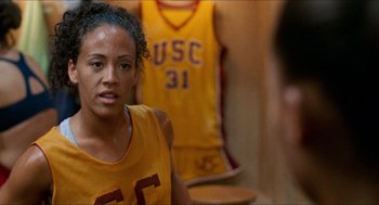 Movie still from “Love & Basketball” (2000), directed by Gina Prince-Bythewood – A young woman in a yellow and red basketball uniform; Close Up shot, Over the shoulder angle