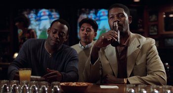 Movie still from “Love & Basketball” (2000), directed by Gina Prince-Bythewood – A group of men sitting at a table drinking beer; Medium shot, Low angle