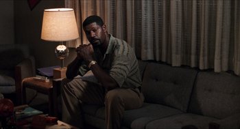 Movie still from “Love & Basketball” (2000), directed by Gina Prince-Bythewood – A man sitting on top of a couch in a living room; Medium shot, High angle