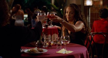Movie still from “Love & Basketball” (2000), directed by Gina Prince-Bythewood – A woman sitting at a table with a glass of red wine; Medium shot, Over the shoulder angle