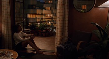 Movie still from “Love & Basketball” (2000), directed by Gina Prince-Bythewood – A person sitting on a chair in a room with potted plants; Wide shot, High angle
