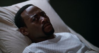 Movie still from “Love & Basketball” (2000), directed by Gina Prince-Bythewood – A man laying in a hospital bed looking sad; Close Up shot, High angle