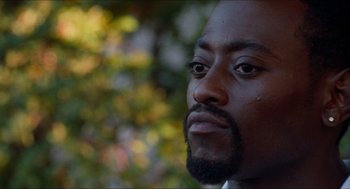 Movie still from “Love & Basketball” (2000), directed by Gina Prince-Bythewood – A man's face with trees in the background; Close Up shot, Over the shoulder angle