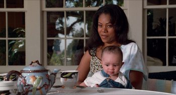 Movie still from “Love & Basketball” (2000), directed by Gina Prince-Bythewood – A woman holding a baby sitting at a dining table; Close Up shot, High angle