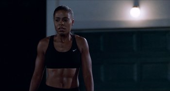 Movie still from “Love & Basketball” (2000), directed by Gina Prince-Bythewood – A woman in a sports bra is standing in a gym; Medium shot, Over the shoulder angle