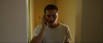 Movie still from “Love” (2015), directed by Gaspar Noé – A young man is talking on a cell phone; Close Up shot, Low angle