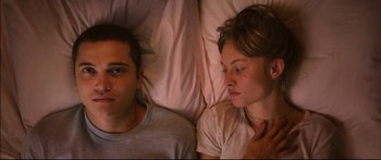 Movie still from “Love” (2015), directed by Gaspar Noé – A man and a woman laying in bed together; Close Up shot, Overhead angle
