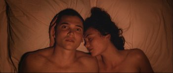 Movie still from “Love” (2015), directed by Gaspar Noé – A man and a woman laying in bed together; Close Up shot, Overhead angle