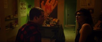 Movie still from “Love” (2015), directed by Gaspar Noé – A young man is looking at a painting in the background; Medium shot, Over the shoulder angle