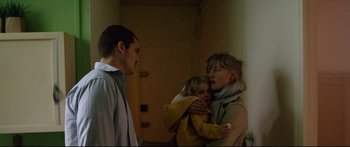 Movie still from “Love” (2015), directed by Gaspar Noé – A woman holding a child in her arms while standing next to a man; Medium shot, Low angle