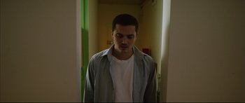 Movie still from “Love” (2015), directed by Gaspar Noé – A young man standing in a doorway with his eyes wide open; Medium shot, Low angle