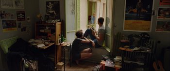 Movie still from “Love” (2015), directed by Gaspar Noé – A man and a woman sitting on the floor of a living room; Wide shot, High angle