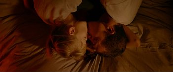 Movie still from “Love” (2015), directed by Gaspar Noé – A man and a woman laying on the ground with their eyes closed; Close Up shot, Overhead angle