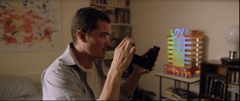 Movie still from “Love” (2015), directed by Gaspar Noé – A man holding a video game controller in his hands; Close Up shot, Over the shoulder angle