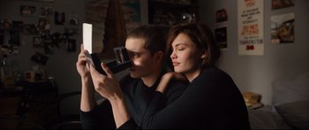Movie still from “Love” (2015), directed by Gaspar Noé – A man and a woman looking at something on a video camera; Medium shot, High angle