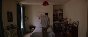 Movie still from “Love” (2015), directed by Gaspar Noé – A man standing on a bed in a room; Wide shot, High angle