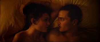Movie still from “Love” (2015), directed by Gaspar Noé – A man and a woman laying in bed together; Close Up shot, Overhead angle