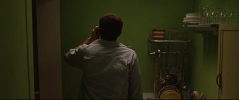 Movie still from “Love” (2015), directed by Gaspar Noé – A man is talking on a cell phone in front of a green wall; Medium shot, High angle