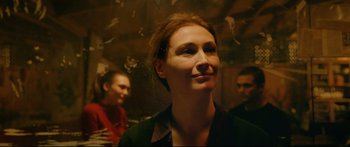Movie still from “Love” (2015), directed by Gaspar Noé – A person smiling with others in the background; Close Up shot, Over the shoulder angle