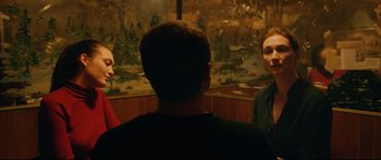 Movie still from “Love” (2015), directed by Gaspar Noé – A group of people standing in front of a painting; Medium shot, Over the shoulder angle