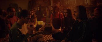 Movie still from “Love” (2015), directed by Gaspar Noé – A group of people sitting on the ground in front of a fireplace; Medium shot, Over the shoulder angle