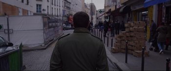 Movie still from “Love” (2015), directed by Gaspar Noé – A man wearing a green jacket walking down a street; Medium shot, Low angle