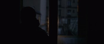 Movie still from “Love” (2015), directed by Gaspar Noé – A person sitting in a dark room looking out of a window; Medium shot, Low angle