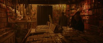 Movie still from “Love” (2015), directed by Gaspar Noé – A man standing in a room filled with lots of books; Wide shot, High angle