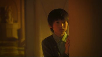 Movie still from “Love Exposure” (2008), directed by Sion Sono – A young boy standing in front of a curtain; Close Up shot, Low angle