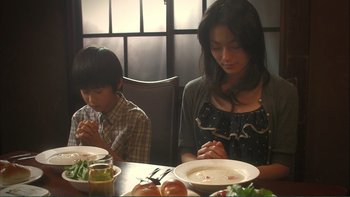 Movie still from “Love Exposure” (2008), directed by Sion Sono – A woman sitting at a table with a bowl of soup; Medium shot, Low angle
