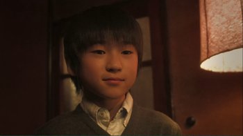 Movie still from “Love Exposure” (2008), directed by Sion Sono – A young boy with a white shirt and a gray sweater; Close Up shot, Low angle