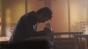 Movie still from “Love Exposure” (2008), directed by Sion Sono – A man sitting in front of a crucifixion cross in a church; Medium shot, Low angle