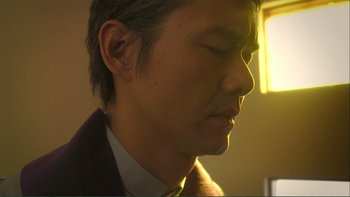 Movie still from “Love Exposure” (2008), directed by Sion Sono – A person wearing a suit and tie; Close Up shot, Low angle