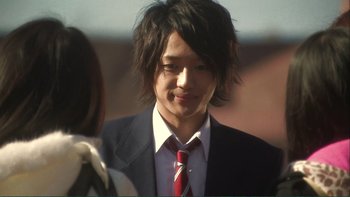 Movie still from “Love Exposure” (2008), directed by Sion Sono – A man in a suit and red tie smiling for the camera; Close Up shot, Over the shoulder angle