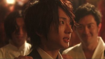 Movie still from “Love Exposure” (2008), directed by Sion Sono – A young man with brown hair and green eyes; Close Up shot, Over the shoulder angle