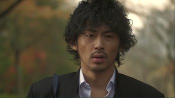 Movie still from “Love Exposure” (2008), directed by Sion Sono – A person wearing a suit and tie; Close Up shot, Over the shoulder angle
