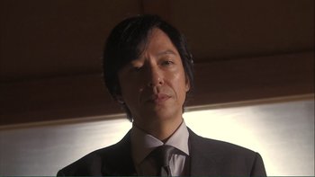 Movie still from “Love Exposure” (2008), directed by Sion Sono – A person wearing a suit and tie; Close Up shot, Low angle