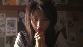 Movie still from “Love Exposure” (2008), directed by Sion Sono – A young woman with long black hair is posing for a picture; Close Up shot, High angle